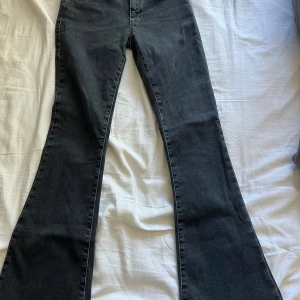 Mörkgrå low flare jeans - Säljer ett par mörkgrå low flare jeans från Bikbok, jätte bra skick förutom lite slitet längst ner på byxbenen, se sista bilden. Passar XS-S