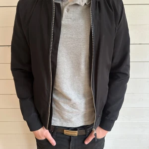 Svart bomberjacka från Zara Man - Säljer en stilren svart bomberjacka från Zara Man. Jackan har dragkedja framtill, ribbade muddar vid ärmslut och midja samt klassisk bomberjacke-passform. Perfekt för dig som gillar enkel och tidlös stil.