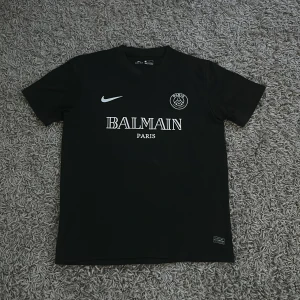 Svart PSG x Balmain fotbollströja från Nike storlek L - Säljer en svart fotbollströja från Nike med PSG och Balmain Paris-tryck i storlek L. Perfekt för sommaren.
