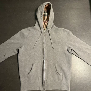 Burberry zip hoodie - Burberry zip hoodie grå i använt skick, aningen urtvättad, 2 fläckar finns och utbytt zipper, storlek M. 