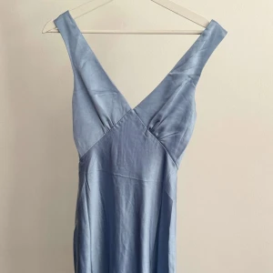 Ljusblå långklänning från Billy J 🦋💙 - Säljer en elegant ljusblå långklänning från Billy J med v-ringad omlott framtill och breda axelband. Klänningen har en figurnära passform och dragkedja i ryggen. Perfekt för sommarens speciella tillfällen. Står ej för frakten!