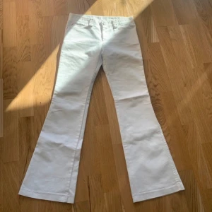 Vita bootcut jeans från Tobacco - Säljer ett par vita lågmidjade jeans från Tobacco med bootcut-passform. Byxorna har fickor fram och bak med snygga röda detaljer vid fickkanterna😻köpte här på plock men säljer igen då de var för stora💗