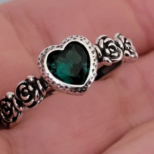  Helt ny Silverring med hjärtformad grön sten och rosdetaljer -  Helt ny Säljer en söt silverring i 925 sterling silver med en hjärtformad grön sten i mitten. Ringen har fina rosdetaljer längs bandet och passar perfekt för dig som gillar unika smycken med romantisk känsla. Justerbar kommer passa de flesta fingrar 