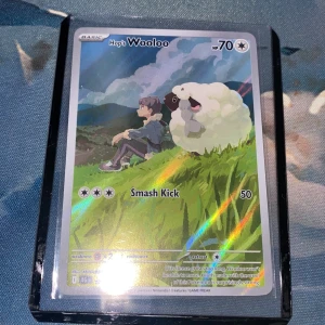 Pokémonkort Hop's Wooloo Holo - Hops Wooloo är ett jättefint kort perfekt för samlare som vill få nya kort i deras församling. Kortet har inga skador och har en stor chans för en psa 10 rating som skulle ta upp värdet från 100 kr till hela 500kr