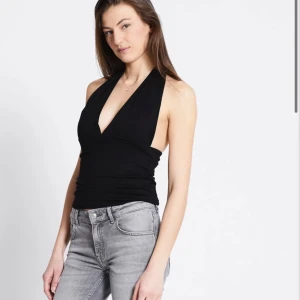 Svart halterneck linne - Säljer ett svart halterneck linne med djup v-ringning och knyt i nacken. Toppen är aldrig använd, endast testad i storlek xs🥰