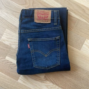 Levi's 511 mörkblå  - Säljer ett par Levi's 511 Slim jeans i mörkblå denim. Klassisk femficksmodell med gul kontrastsöm och läderpatch bak i midjan. Snygg slim fit som passar till många olika stilar. Passar 160 cm lång 
