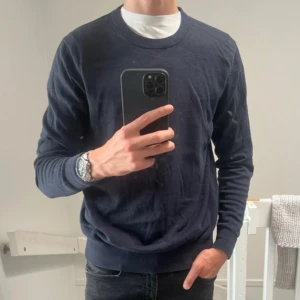 Mörkblå bomullströja These Glory Days - Snygg mörkblå tröja från These Glory Days i mjuk bomull. Klassisk rund halsringning och ribbade muddar vid ärmslut och nederkant. Perfekt basic att ha i garderoben och lätt att matcha med jeans eller chinos.