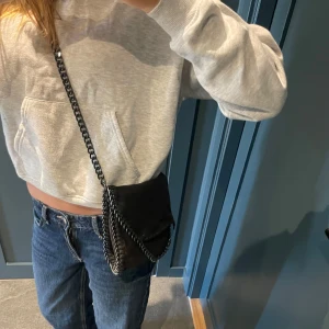 Svart axelväska med kedjedetaljer - Säljer en svart axelväska med snygga silverfärgade kedjor.