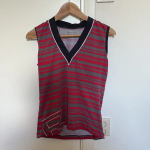 Vintage träningslinne - Träningslinne i röd/grå randigt mönster. Står strl XL i den och den sitter lite baggy på mig som bär S i vanliga fall