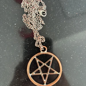 Halsband med pentagram i silver och brons - Coolt halsband med en rund berlock i bronsfärg och ett pentagram i silverfärgad metall. Kedjan är tunn och silverfärgad med klassisk låsning. Perfekt accessoar för dig som gillar alternativ stil eller vill sticka ut.