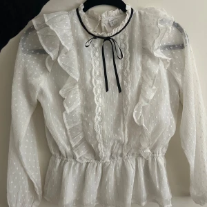 Unik blus med fina detaljer - Supersöt blus från Lindex utan defekter. Fina detaljer med spets och en rosett runt halsen💕💕💞💞Storlek 152 men passar XS! 