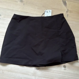 Svart kortkjol i bomull - Enkel svart kortkjol i bomull med rak passform och liten slits framtill. Det är inbyggda shorts/en byxkjol med kjol både bak och framtill 