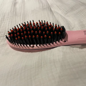 Rosa plattborste - Säljer en rosa elektrisk plattborste från Emerio. Borsten har svarta piggar med röda toppar och är perfekt för att styla håret snabbt. Utrustad med digital display och knappar för temperaturkontroll. Snygg och smidig design. Knappt använd