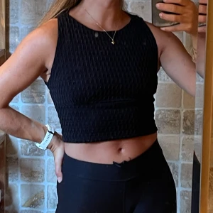 Svart topp från Zara - Säljer en svart croppad topp från Zara Trafaluc. Toppen är ärmlös med rund halsringning och har en snygg strukturerad yta i tyget. Perfekt till både jeans och kjol för en trendig look.