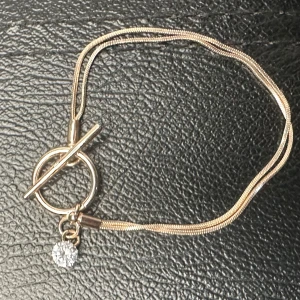 Roséguldfärgat vintagearmband  - Elegant skandinavisk design - Retro - 90-tal 00-tal - Scandi Style - Elegant armband i roséguldfärgad metall med stilren ormkedja och toggle-lås. Litet hänge med gnistrande sten ger diskret glamour. Designen är typisk för 2010-talets skandinaviska smyckestrend, liknande Edblad eller SNÖ. Ca 18 cm långt. Mycket fint skick.  Priset är fast – men jag erbjuder rabatt vid köp av flera saker. Jag rensar smyckesgömman, så kika gärna på mina andra annonser också!  ⸻ 