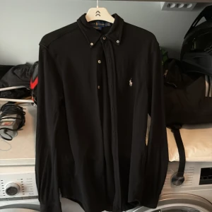 Svart Ralph lauren skjorta - En svart Ralph lauren skjorta som inte kan gå fel och passar nästintill allt, skön skjorta i mycket bra skick!