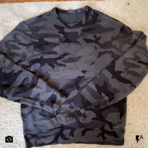  Polo Ralph Lauren - Snygg grå sweatshirt från Polo Ralph Lauren med mörkgrått camouflage- stil. Denna tröja är väldigt unik och svår att hitta, till ett bra pris såklart!