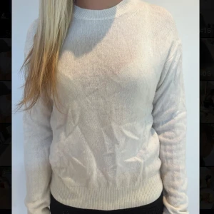 Vit stickad tröja med rund hals - En enkel och stilren vit stickad tröja med rund halsringning och långa ärmar. Tröjan har ribbade muddar vid ärmslut och nederkant. Tröjan är inte strykt men blir snyggare när den är det.