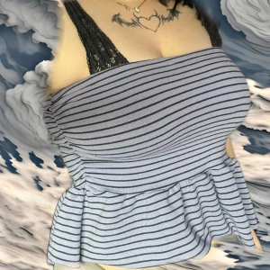 Randig tubtopp från Motel, volang - Superfin tubtopp från Motel i ljuslila med svarta ränder. Toppen är bandeau-modell och har en volang nertill som ger en söt och trendig look. Perfekt att styla med jeans eller kjol för en cool vibe. ORD pris: 619kr