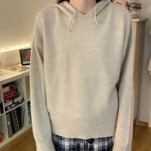 Beige stickad hoodie från Gina Tricot Young - Supermjuk och mysig beige stickad hoodie från Gina Tricot Young i storlek 170. Tröjan har huva med snörning, ribbade muddar och lång ärm. Perfekt för lager-på-lager och chill dagar. Enkel och stilren design som passar till allt. Hoodien har små tecken på användning så som trådar men inget som syns.