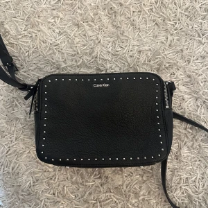 Svart axelväska Calvin Klein skinn - Snygg svart axelväska från Calvin Klein.  Väskan har justerbar rem och två stora fack med dragkedja, den är väldigt rymlig och man får plats med nästan allt i den!