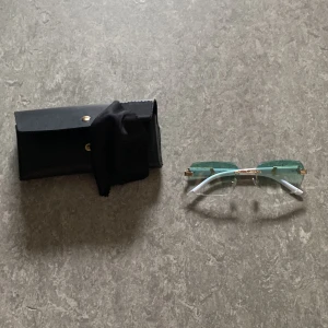 Unika glasögon med gröna glas - Säljer ett par riktigt snygga glasögon med rektangulära gröna glas och gulddetaljer. Skalmarna har ett coolt marmormönster i svart och vitt. Kommer med svart fodral och putsduk. Perfekt för dig som vill sticka ut med din stil.