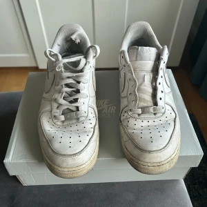 Nike Air Force 1 vita sneakers strl 44 - Klassiska Nike Air Force 1 i helvitt skinn med rund tå och snörning. Snygg low-top modell med ikonisk sula och Nike-logga på sidan. Perfekta för dig som gillar streetstyle och tidlös design.