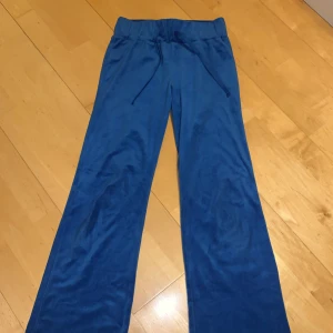 Blå mjukisbyxor från H&M Divided - Blå mjukisbyxor från H&M Divided med skön loose passform. Tillverkade i mjukt, glansigt polyestertyg som känns riktigt bekvämt. Perfekta för chill dagar eller när du vill ha något avslappnat men ändå snyggt. Storlekslappen är borta men jag skulle säga att dem är runt 142-158.