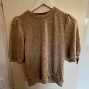 Beige puffärm tröja med kort ärm - Supermjuk beige tröja med puffiga korta ärmar och rund hals. Materialet känns som bomull eller en mjuk syntetmix🌼