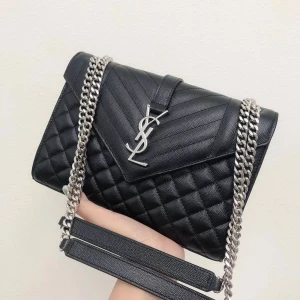Svart quiltad axelväska från Saint Laurent - Säljer en svart quiltad axelväska från Saint Laurent med silverfärgad kedjerem och ikoniskt YSL-emblem framtill. Väskan är tillverkad i skinn och har ett stilrent, lyxigt uttryck med snygga detaljer och praktiskt innerfack.