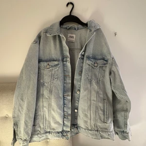 Ljusblå oversized jeansjacka från Zara - Säljer en ljusblå jeansjacka från Zara i oversized modell. Jackan har klassisk krage, knappar framtill och två bröstfickor med lock. Perfekt att slänga över en hoodie eller t-shirt för en chill look.