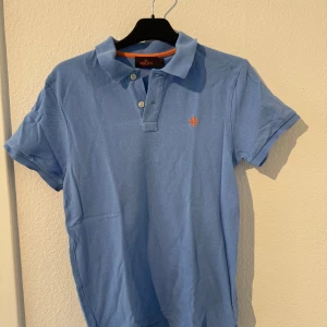 Ljusblå pikétröja från Morris - Snygg ljusblå pikétröja från Morris med klassisk krage och knappar framtill. 