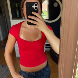 Jättesöt röd topp - Sååå snygg röd  topp med korta ärmar och U-ringad halsringning. Toppen har ribbat tyg, rynkdetalj framtill och söt spetskant längs urringningen. Endast provad