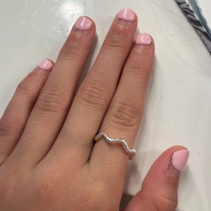 Vågformad silverring - Säljer en snygg vågformad ring i silver. Perfekt för dig som gillar unika och trendiga smycken. Ringen har en cool, böljande design som sticker ut och passar till alla outfits. 