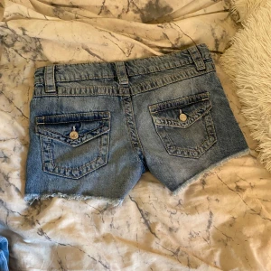 Blå jeansshorts - Snygga blå jeansshorts med  slitna detaljer. Shortsen är lågmidjade och är bara andvända en gång. De är i storlek 164