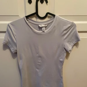 Vit basic t-shirt från H&M XS - Enkel och stilren vit t-shirt från H&M i storlek XS. T-shirten har rund halsringning och korta ärmar, perfekt för en clean och avslappnad look. Tillverkad i mjuk bomull som känns skön mot huden.
