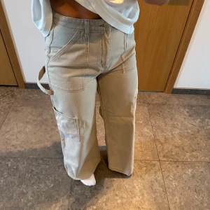 Beige cargopants med wide fit - Säljer ett par beige cargopants med breda ben och flera fickor på sidorna. Snygg beige färg. Från NAKD. Storlek 34 men stora i storlek 