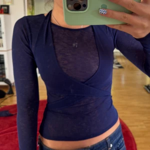 Mörkblå omlottopp med lång ärm - Säljer en mörkblå, tight och transparent omlottopp med lång ärm