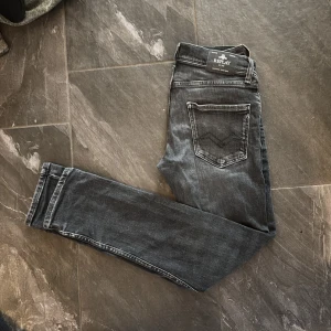 Svarta replay jeans - Snygga svarta jeans från Replay med slim passform och klassisk femficksdesign. Jeansen har slitna detaljer, samt Replay-logga vid fickan. 