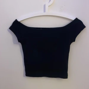 Svart offshoulder topp Pull&Bear S - Svart croppad topp från Pull&Bear i storlek S. Modellen är offshoulder med korta ärmar och har en tight passform. 