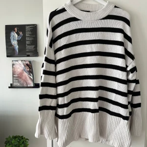 Randig stickad tröja Gina Tricot XL - Oversized stickad tröja från Gina Tricot i svart och vitt med breda ränder. Tröjan har lång ärm, ribbade muddar och en rund halsringning. Perfekt för lager-på-lager och chill vibes.
