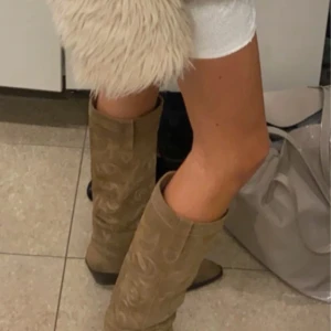 Beige cowboy boots med broderad detalj, beige/brun - Snygga beige cowboy boots med broderade mönster längs skaftet. perfekt färg, modell och höjd!!! köpte dom på plick tidigare men får inte användning av dem så säljer vidare. de är beige/bruna. Har används två gånger och har några små fläckar nere vid foten😙💘