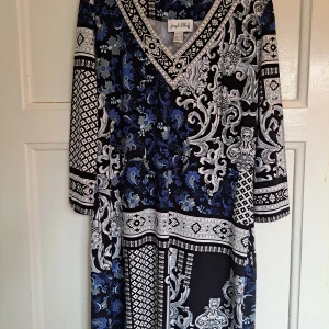 Mönstrad klänning från Joseph Ribkoff - Snygg långärmad klänning från Joseph Ribkoff med v-ringning. Klänningen har ett unikt mönster i blått, svart och vitt med både blommiga och grafiska detaljer. Mjuk och följsam polyester som sitter bekvämt och ger en cool look.