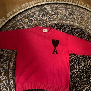 Rosa stickad tröja från Ami Paris - Säljer en äkta rosa stickad tröja från Ami Paris med svart hjärta och A-logga på bröstet. Tröjan har rund halsringning, ribbade muddar och lång ärm. Stretchig material och passar dig som har M också, priset går att alltid diskuteras 