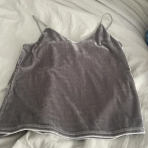 Grå sammetslinne från Bik Bok XS - Supersnyggt grått linne i sammet från Bik Bok med tunna axelband och enkel, rak passform. Perfekt att styla med jeans eller kjol för en trendig look. Mjuk och glansig yta som ger en lyxig känsla.
