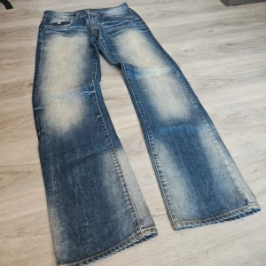 Blå jeans från Rhode Island - Snygga blå jeans från Rhode Island Jeansen har klassisk femficksdesign, ljusa slitningar framtill och bak samt råa kanter nertill. Tillverkade i robust denim med cool vintagekänsla och kontrastsömmar. Midja:40cm innerben 110cm 