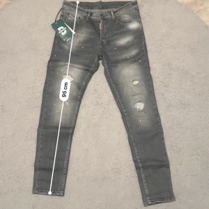 Grå Dsquared2 jeans med slitningar - Dsquared2 jeans – herr Exklusiva Dsquared2 jeans i grå tvätt med slitna detaljer och färgstänk – riktigt snygga och trendiga! Perfekt passform (slim fit/skinny).  📏 Mått: 	•	Längd: ca 95 cm 	•	Midja: ca 42 cm (plattmått)  ✅ Äkta Dsquared2 – med tagg 👖 Slim fit 🎨 Grå tvätt, slitna detaljer, unika färgstänk  Jag är aktiv 24/7, så svarar snabbt på frågor. Vid en snabb affär kan jag självklart gå ner lite i pris. 💸 