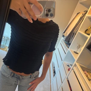 Blå ribbad topp med vågig kant - Säljer en marin blå topp med ribbad struktur och vågiga kanter. Endast använd 1 gång