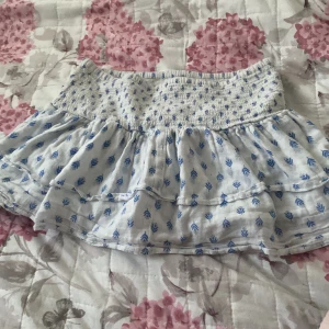 Ljusblå kortkjol med volang - Supersöt ljusblå kortkjol med blått mönster från Gina Tricot Young. Storlek 170 i Young men jag e oftast storlek S o den passar mig bra 