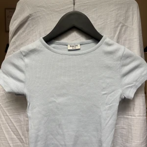 Ljusblå ribbad topp  - En ljusblå lite croppad ribbad topp från Kappahl i storlek 146/152 men är som en Xsmed rund halsringning och korta ärmar. Enkel och fräsch design som passar perfekt till jeans eller kjol. Den är använd några enstaka gånger! Kontakta om du har några funderingar!!❤️